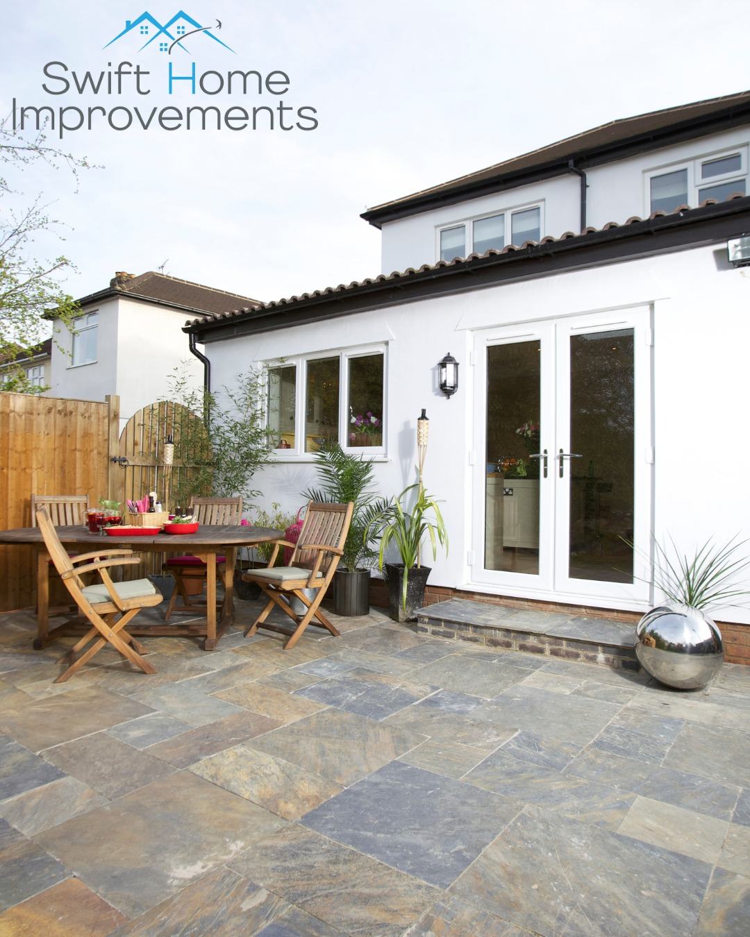 White uPVC French patio doors and casement windows on a white rendered rear extension with a sandstone patio dining area, a Swift Home Improvements project