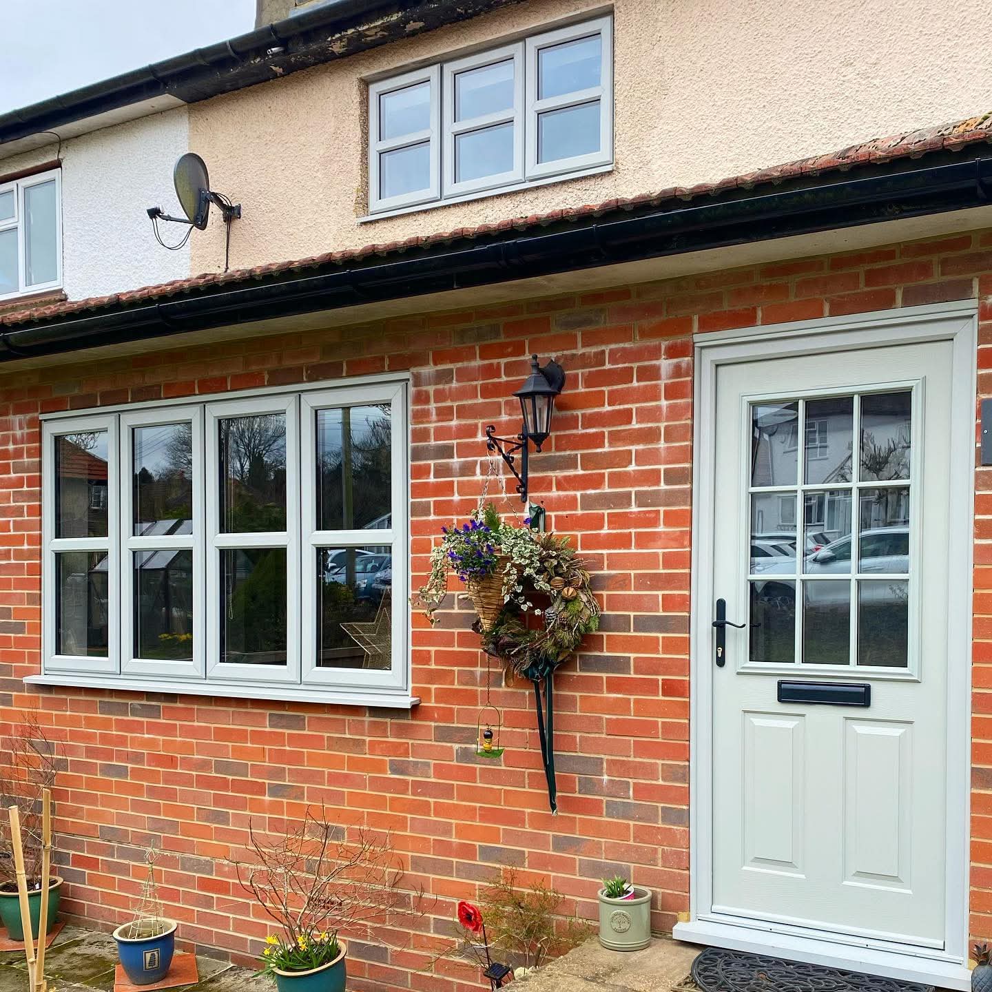 Red brick semi-detached home with new white uPVC casement windows and a composite front door