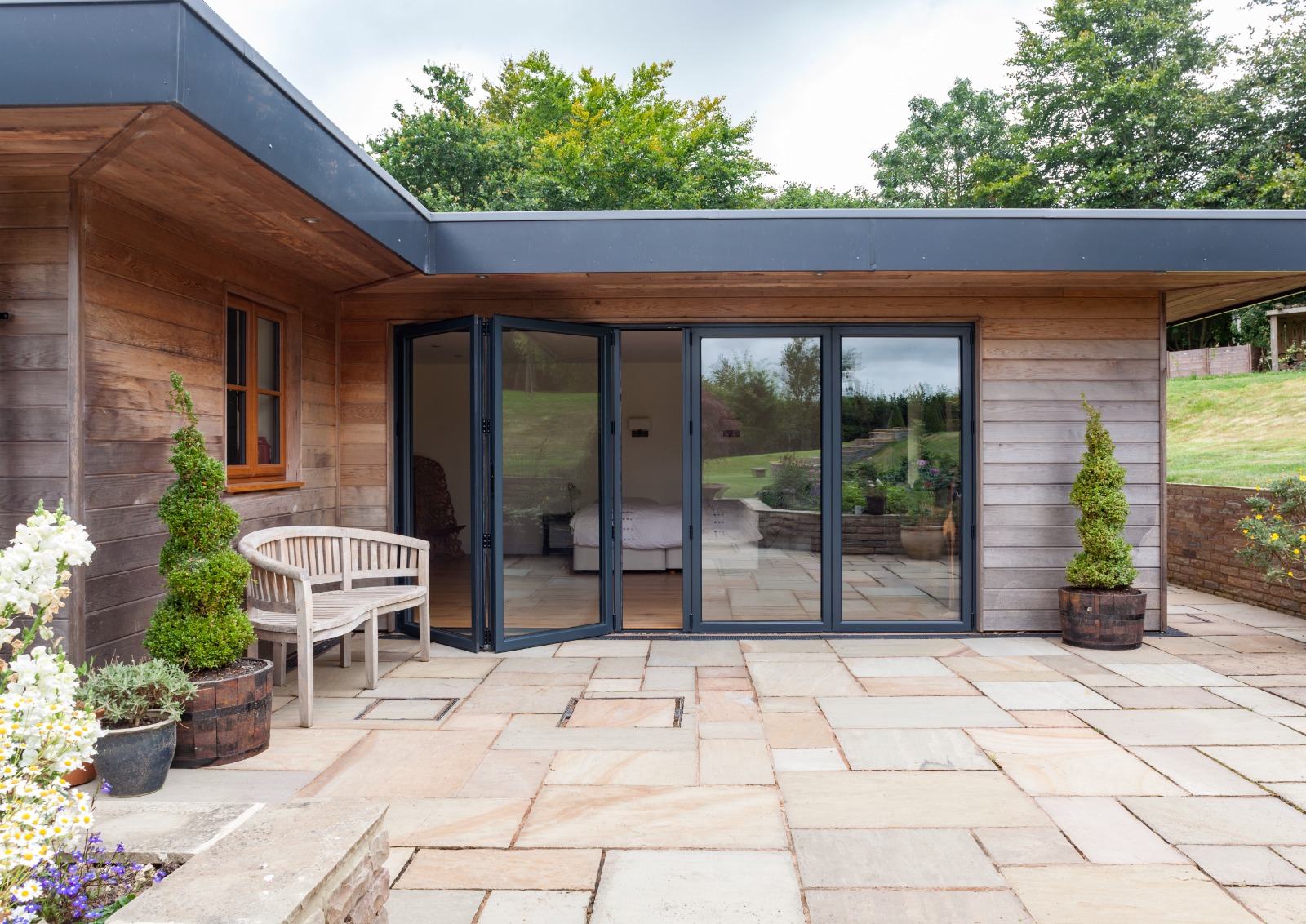 Open aluminium bi-fold doors on a garden extension with sandstone patio in Surrey