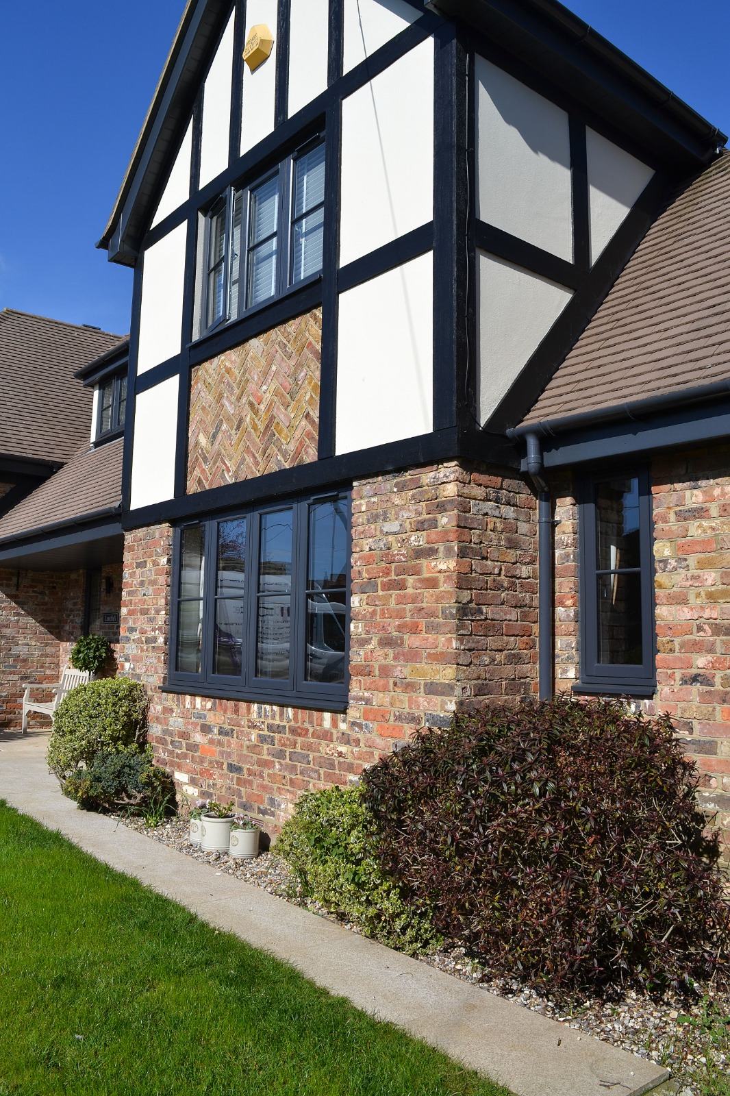 Anthracite grey uPVC casement windows installed on a mock-Tudor brick and render family home
