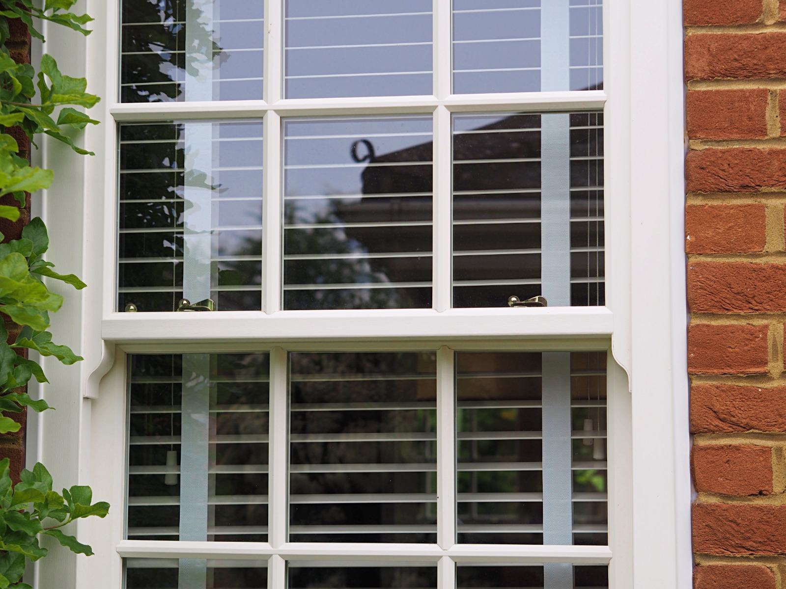 Close-up of a white sliding sash window fitted into a period London brick facade