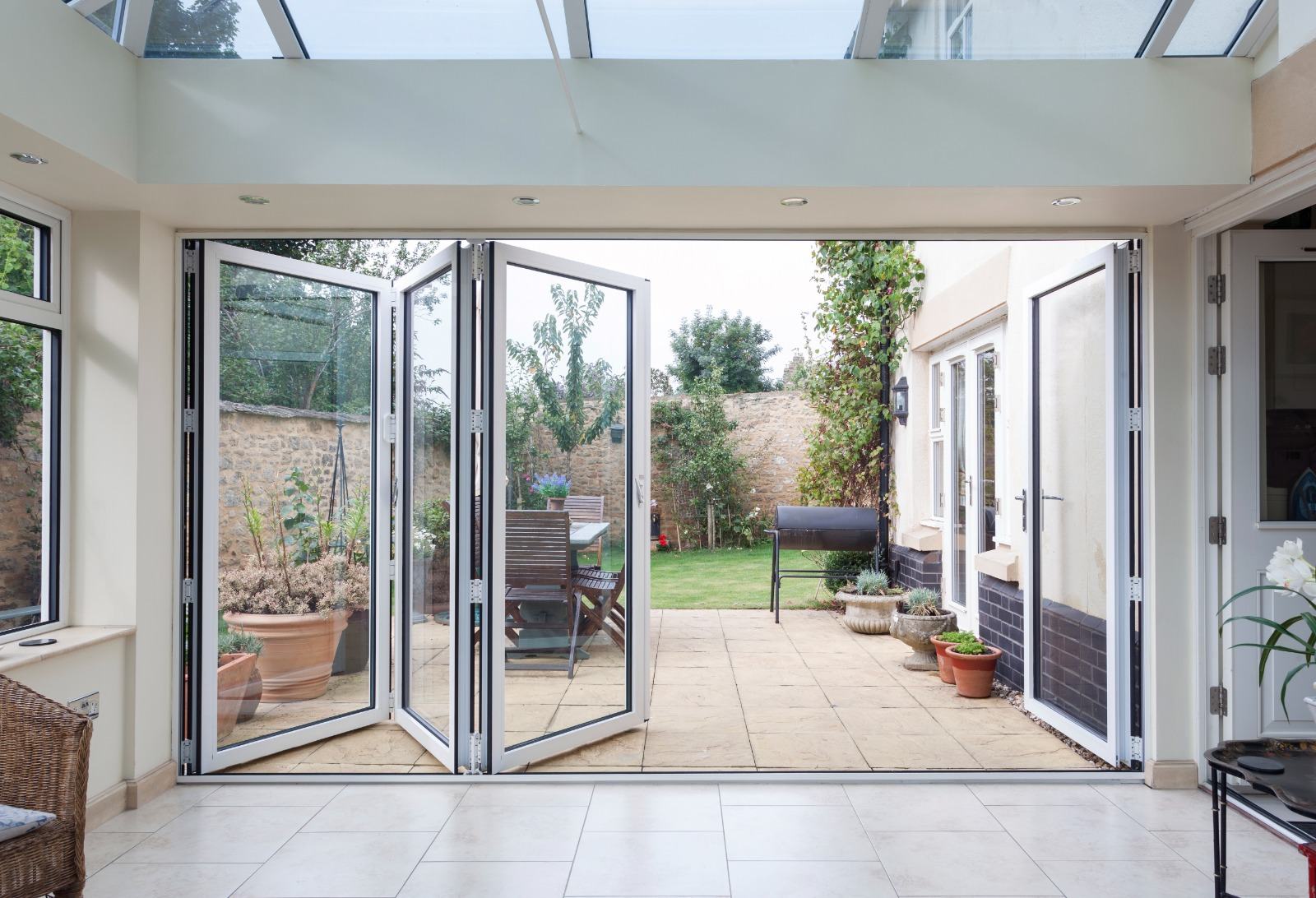 Interior view of a conservatory extension with aluminium bi-fold doors, glass roof and garden view
